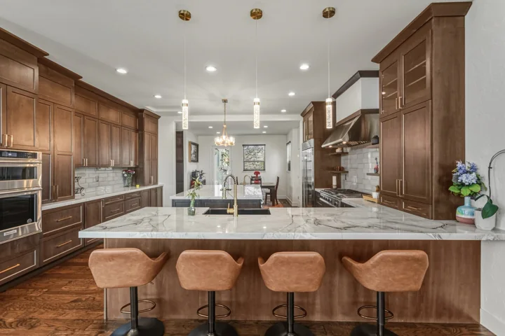 Wood cabinetry, stone island and upholstered stools in a kitchen